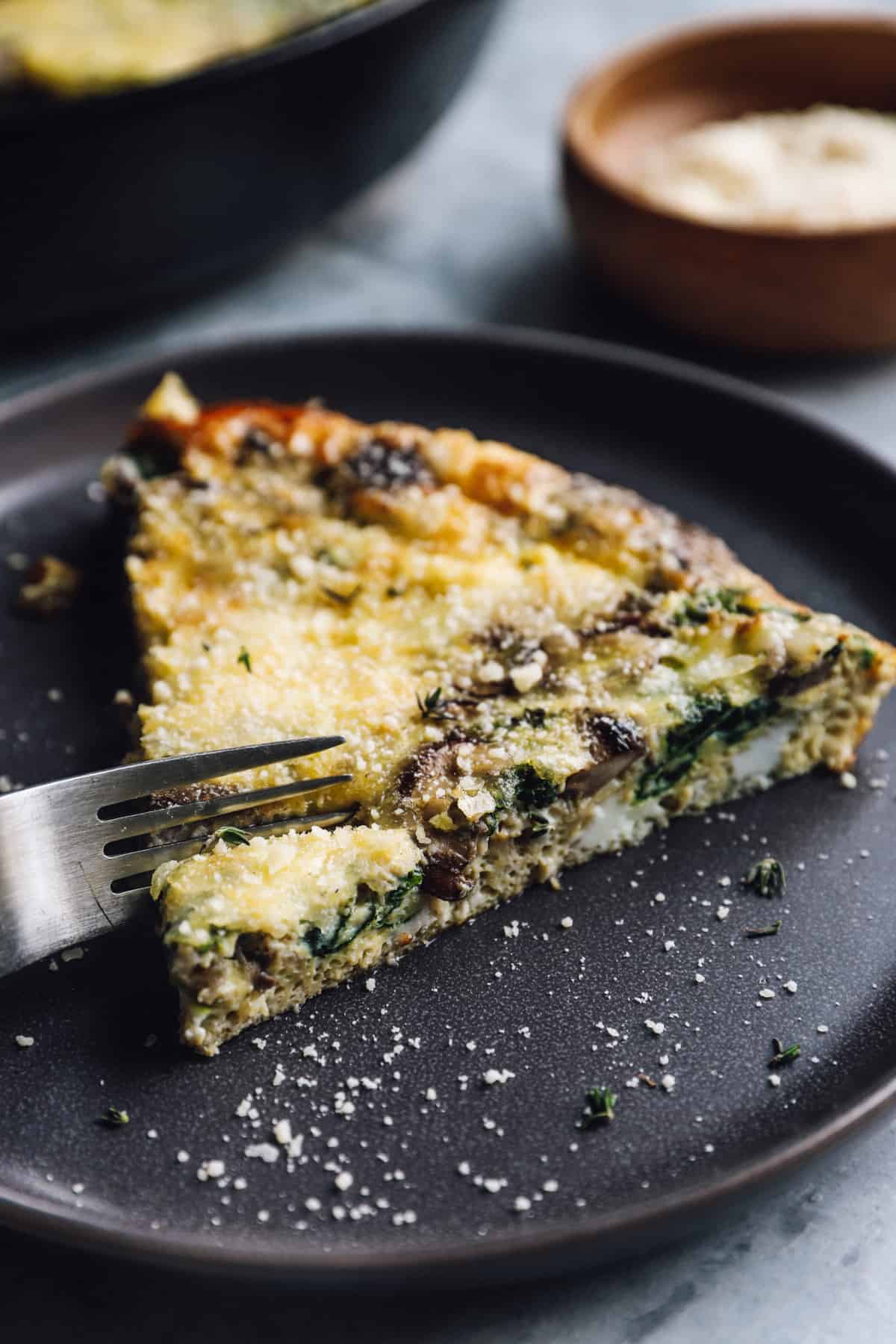 A fork slicing into a piece if mushroom frittata.