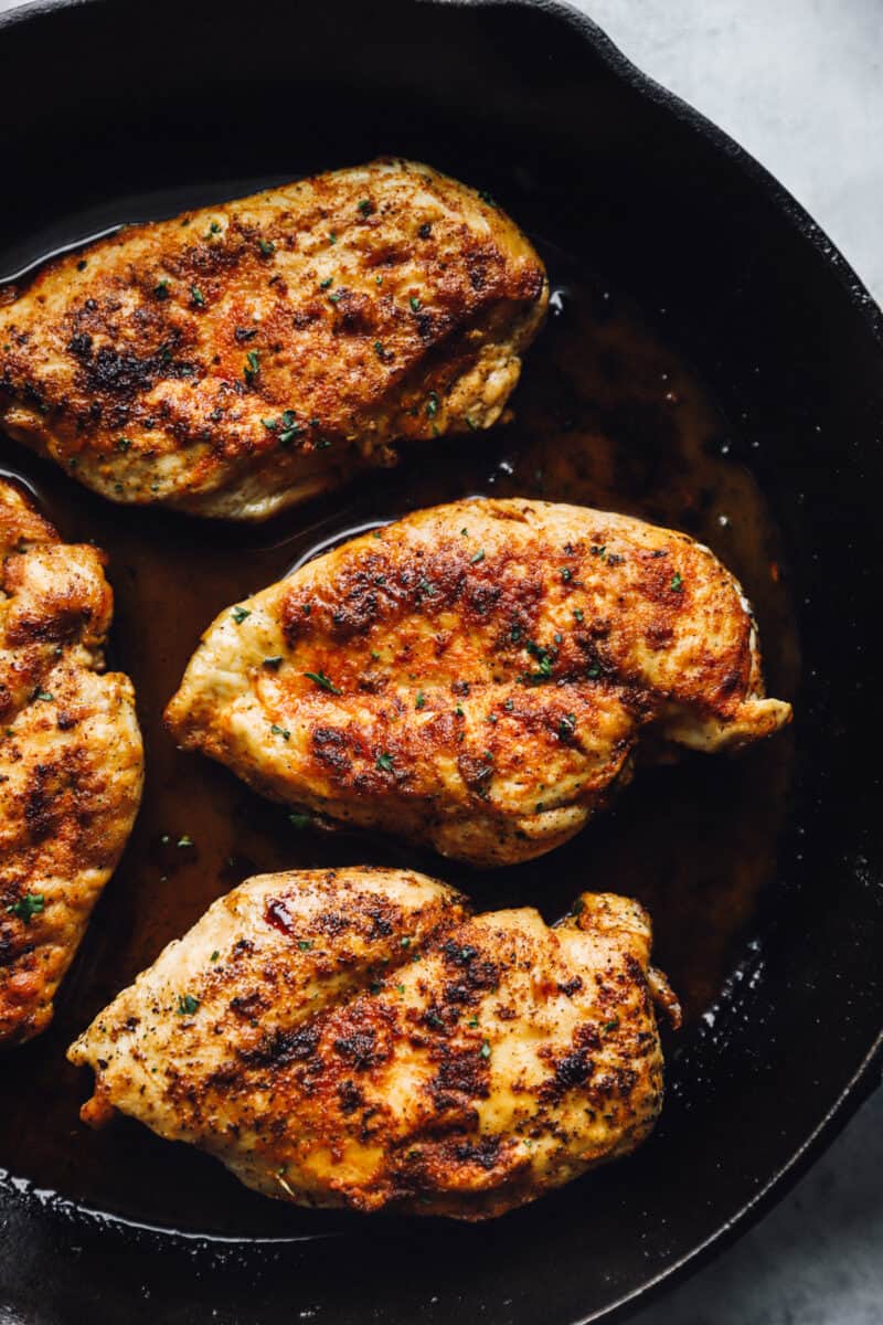 chicken breasts searing in a cast iron skillet