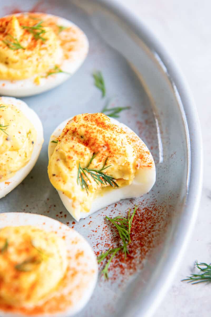 close up on a plate of deviled eggs, one with a bite taken out