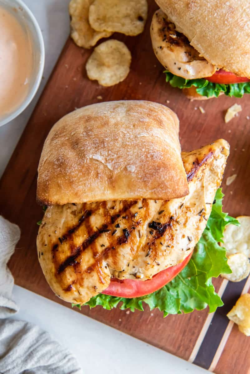 overhead view of a grilled chicken sandwich, the top bun is half-way off the sandwich to show the grilled chicken