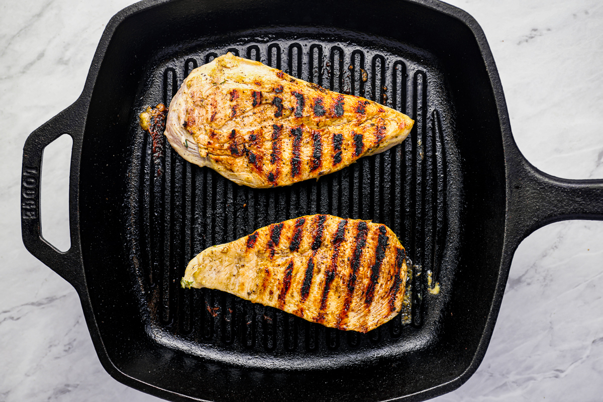 2 chicken breasts grilling in a grill pan.