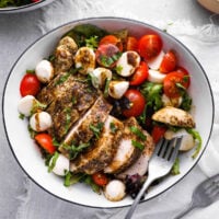 chicken caprese salad in a white bowl with a fork