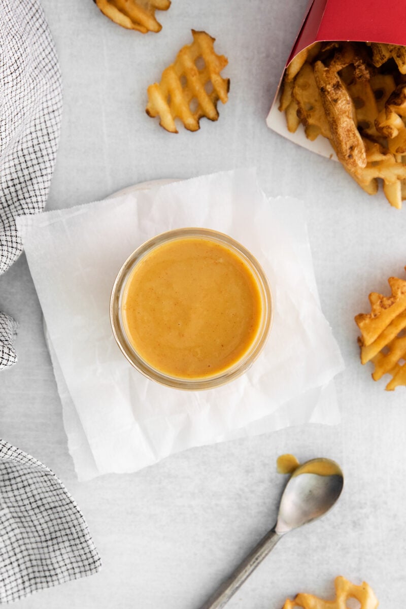 overhead view of chick fil a sauce in a glass jar on a white napkin.