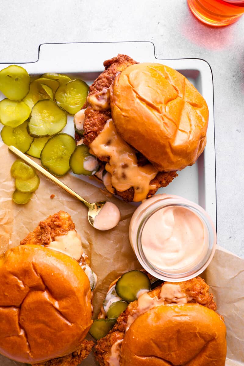 fried chicken sandwiches on a tray with pickles and sauce