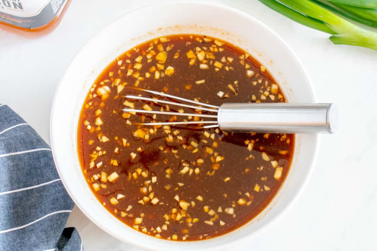 sauce for bourbon chicken in a white bowl with a whisk.