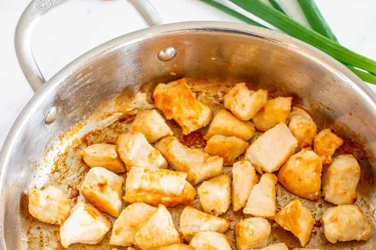 cooked diced chicken in a frying pan.