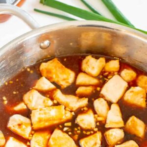 bourbon sauce poured over diced chicken in a frying pan.