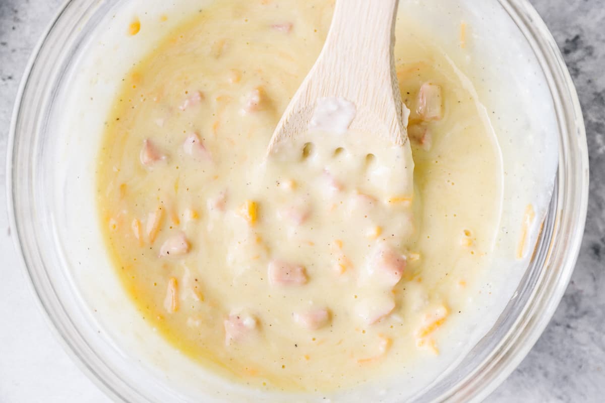 Egg, ham, and cheese mixture in a glass mixing bowl.