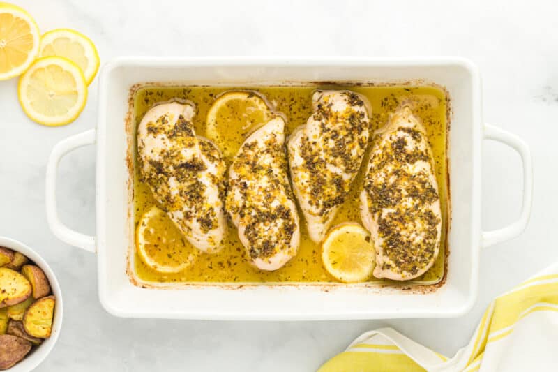 4 baked lemon butter chicken breasts in a rectangular baking dish.