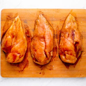 marinated chicken breasts lined up on a cutting board