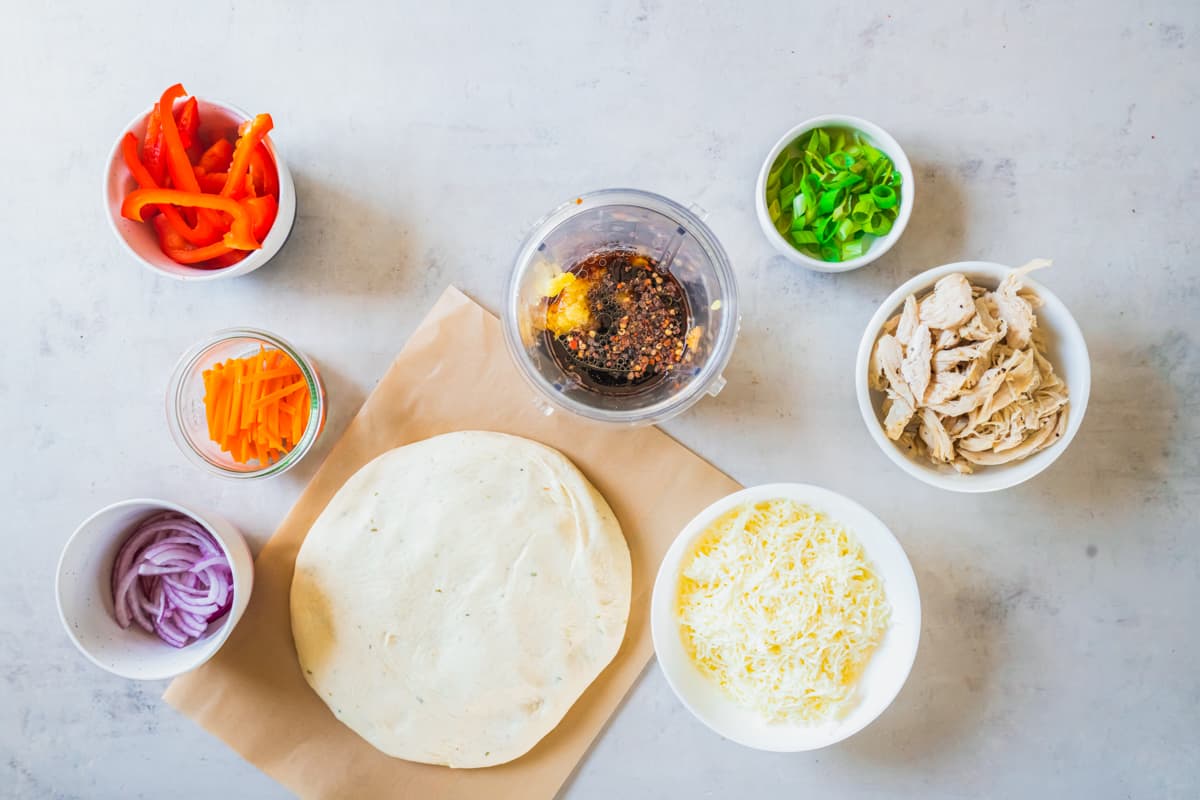 Chicken quesadilla ingredients and Thai chicken pizza laid out on a table.
