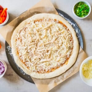 pizza crust topped with sauce, cheese, and chicken, uncooked