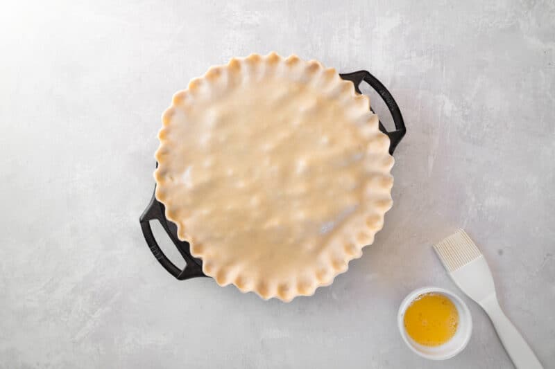 crimped unbaked chicken bacon pot pie in a pie pan.