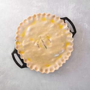 egg washed unbaked chicken bacon pot pie in a pie pan.