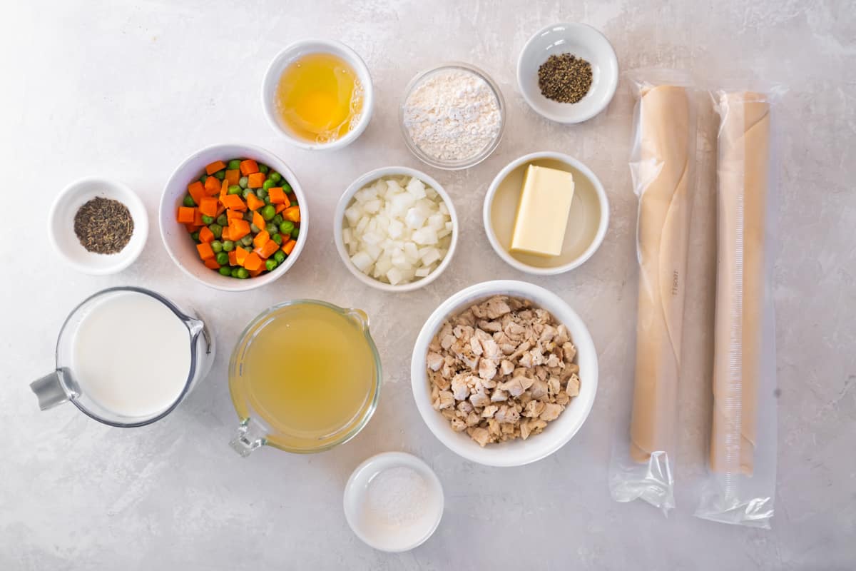 Ingredients for chicken pot pie hand pies: diced chicken, refrigerated pie crusts, peas and carrots, broth, butter, onions, flour, and butter.