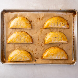 6 baked chicken hand pies on a baking sheet.