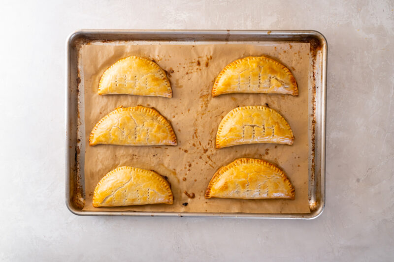 6 baked chicken hand pies on a baking sheet.