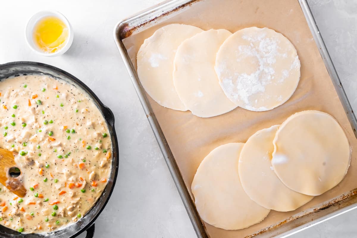 Six small circles of pie dough on a baking sheet.