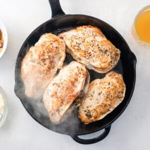 4 seared chicken breasts in a cast iron pan.