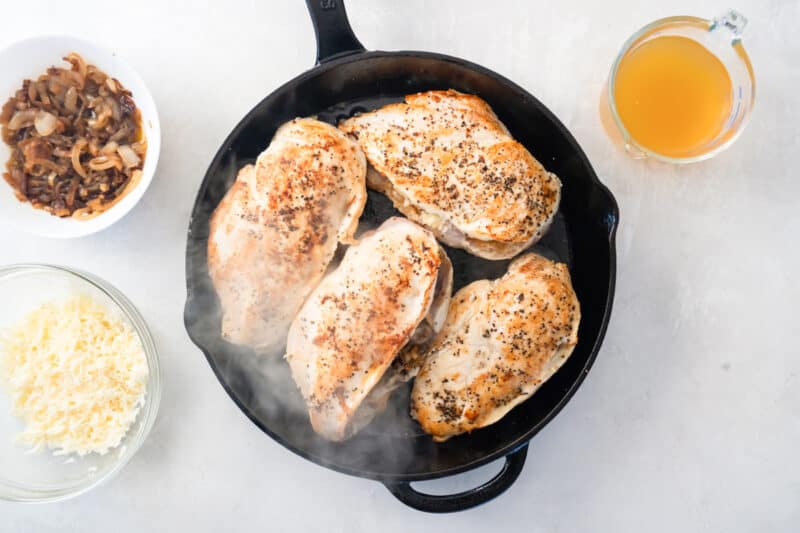 4 seared chicken breasts in a cast iron pan.