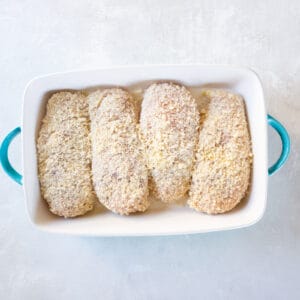 breaded unbaked ranch parmesan chicken in a blue and white baking dish.