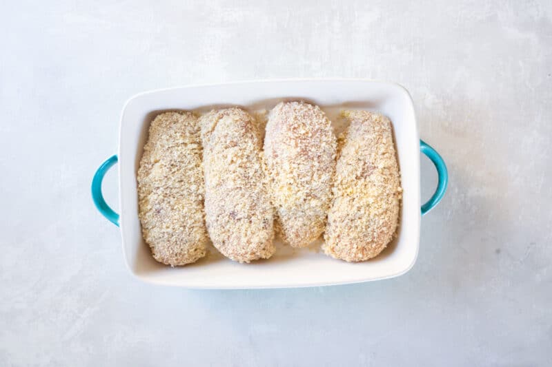 breaded unbaked ranch parmesan chicken in a blue and white baking dish.