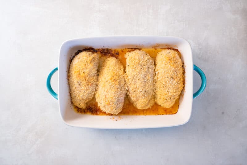 baked parmesan ranch chicken in a white and blue baking dish.