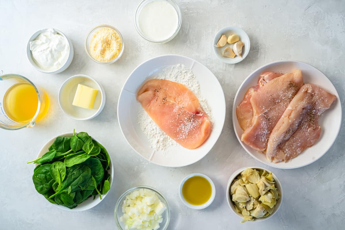 a thin sliced chicken breast dredged in flour in a white bowl.