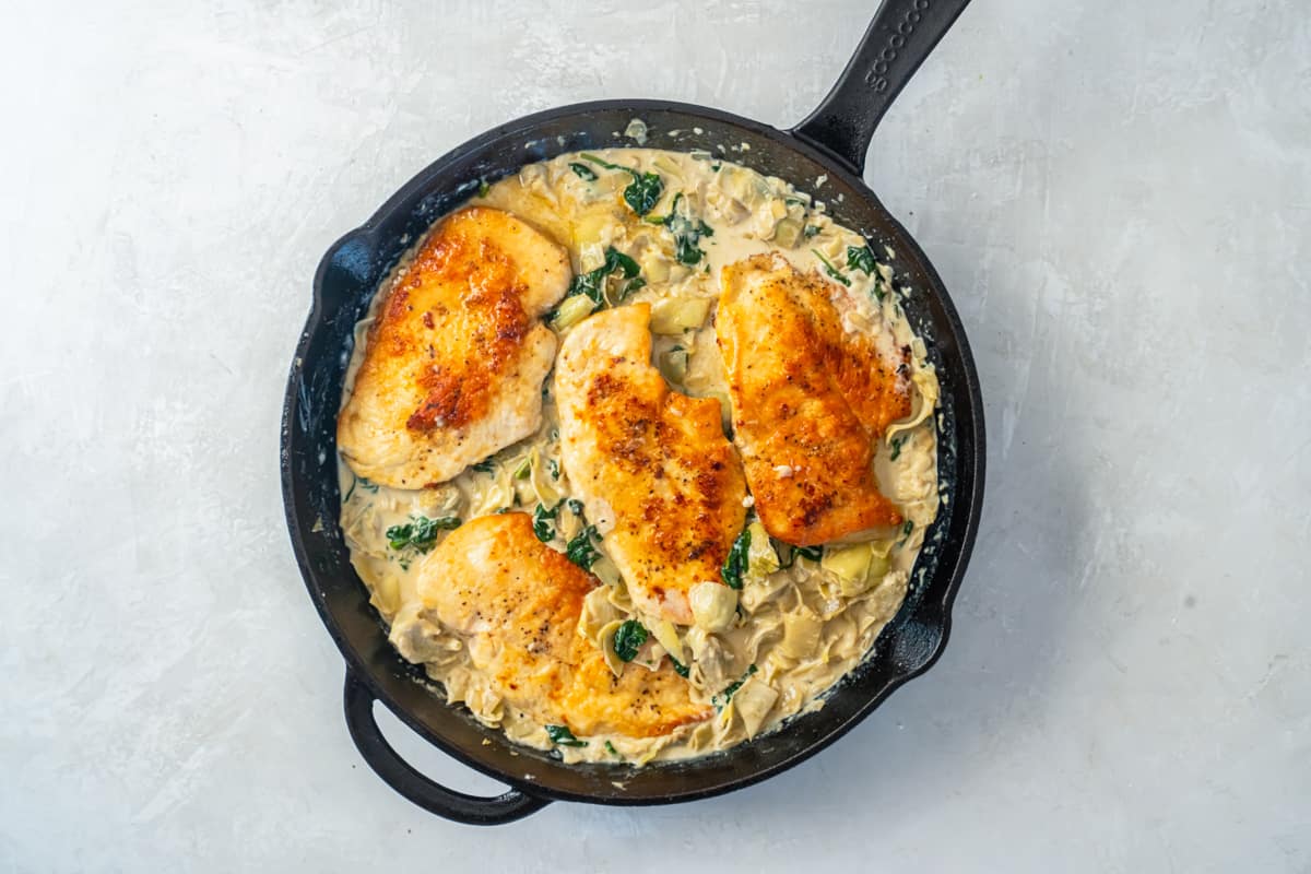 spinach artichoke chicken in a cast iron skillet.