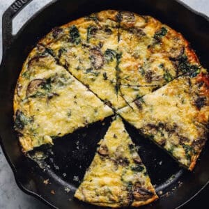 overhead view of a cut and partially eaten mushroom frittata in a cast iron skillet.