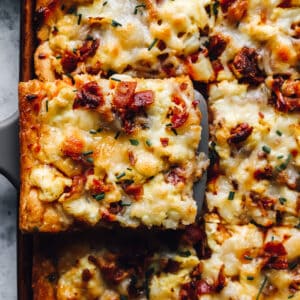 a slice of crescent roll breakfast pizza being lifted from a sheet pan by a spatula.