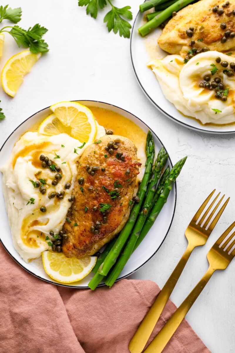 plates with chicken piccata and mashed potatoes on a tablescape with forks
