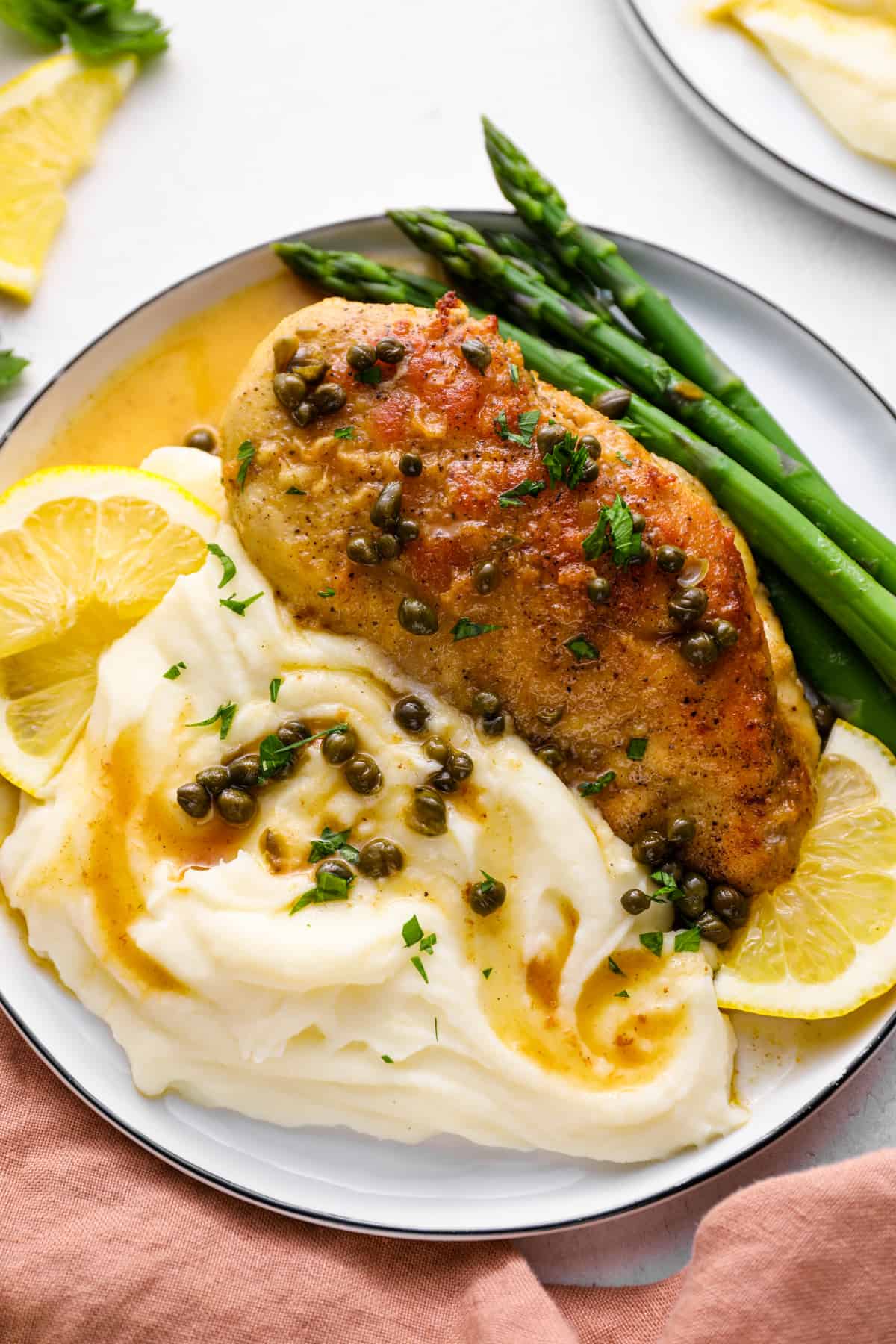 stuffed chicken piccata on a plate with mashed potatoes and asparagus