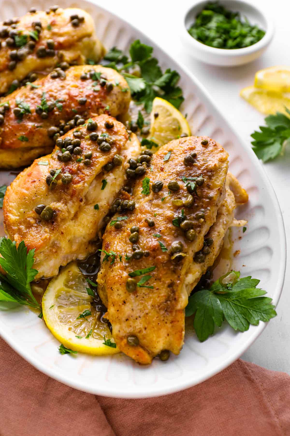 A serving platter of cheese stuffed chicken breasts with piccata sauce.