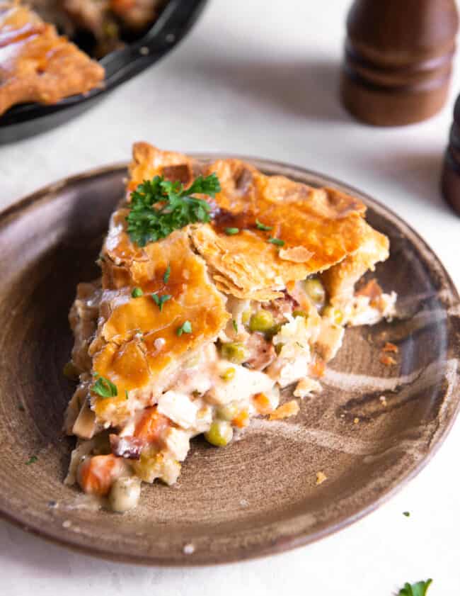 a slice of chicken bacon pot pie on a brown plate.