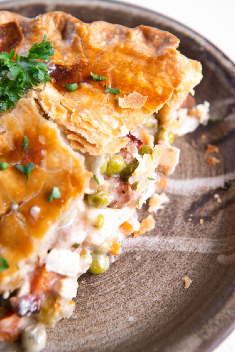 close up of a slice of chicken bacon pot pie on a brown plate.