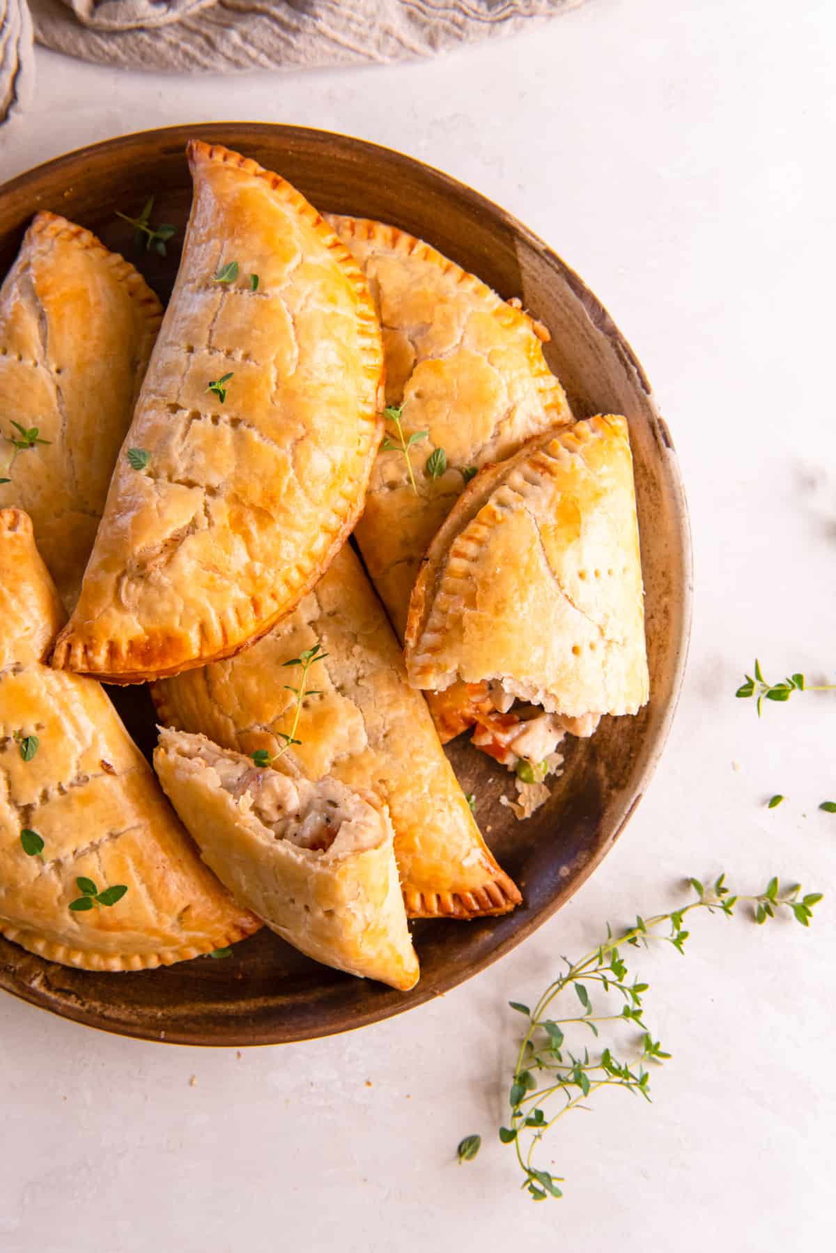 A plate of handheld chicken pot pies in golden pie crusts.