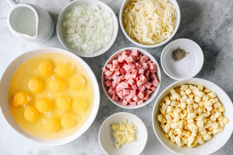 overhead view of ingredients for ham and cheese frittata in individual bowls.