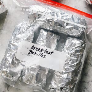 breakfast burritos wrapped in foil and inside of a freezer bag