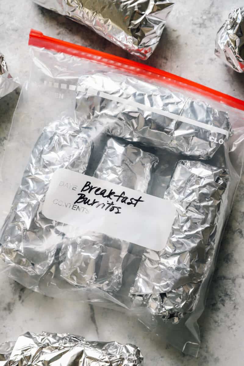 breakfast burritos wrapped in foil and inside of a freezer bag
