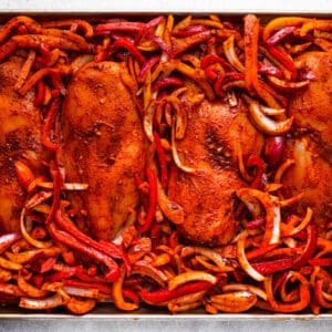 seasoned chicken breasts and peppers on a sheet pan