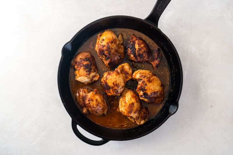 chicken thighs cooling in seasoned butter in a skillet