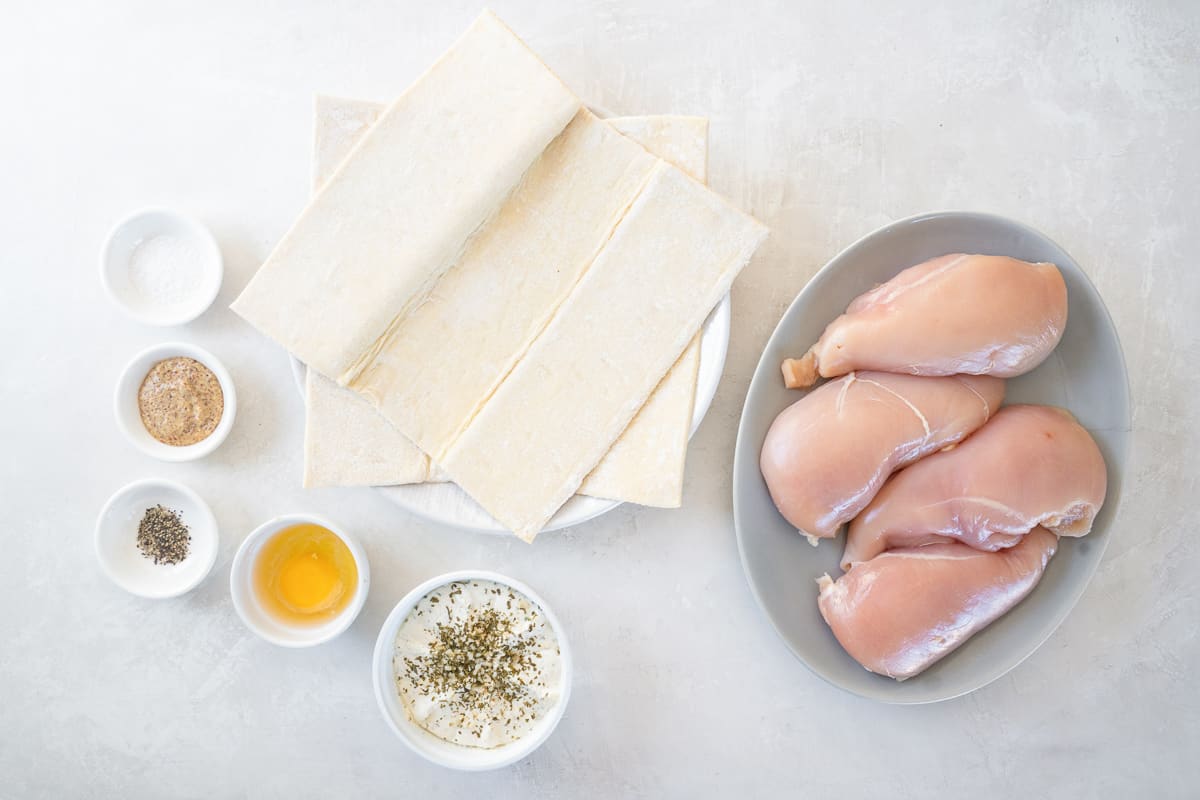 Ingredients for chicken alouette: puff pastry sheets, raw chicken breasts, alouette cheese, and spices.