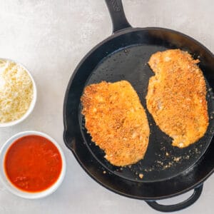 pan fried breaded chicken breasts in a cast iron skillet.