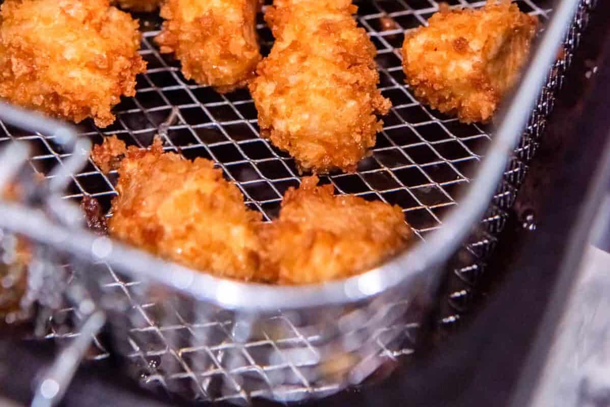 15 pieces of fried popcorn chicken in a fryer basket.