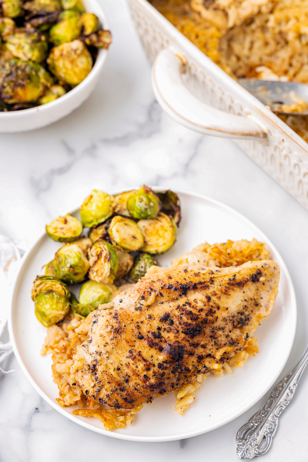 no peek chicken and rice on a white plate with brussels sprouts.