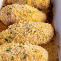 close up of 4 parmesan ranch chicken breasts in a blue and white baking dish.