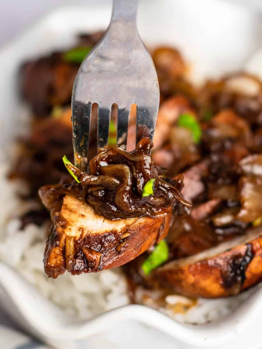 close up view of a bite of balsamic glazed chicken on a fork.