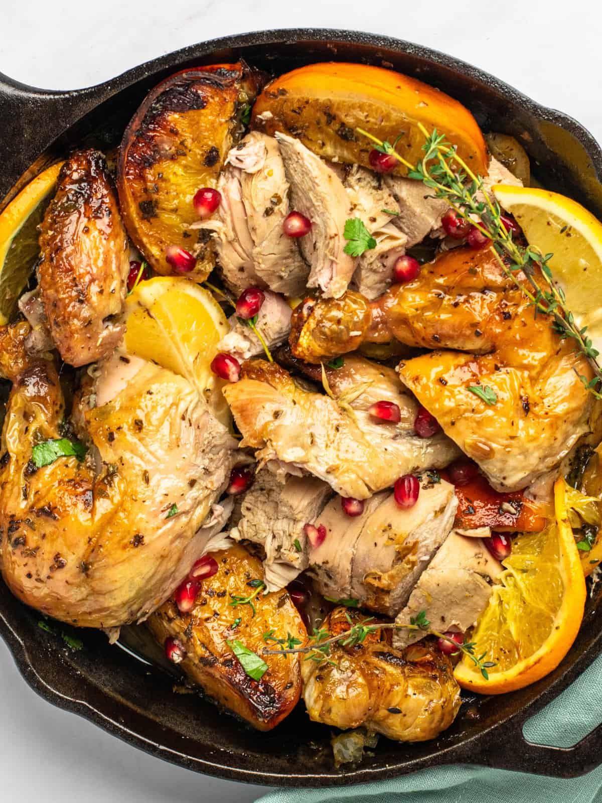 overhead view of christmas chicken cut into pieces in a cast iron skillet.