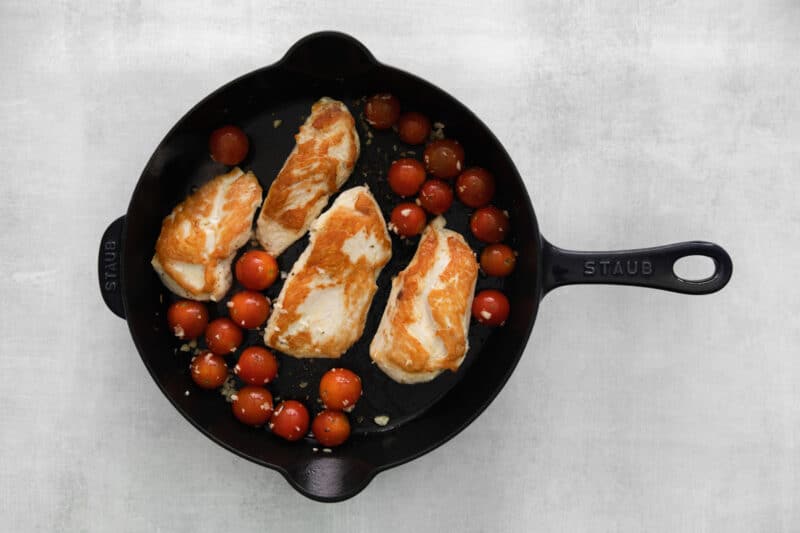 chicken breasts in a skillet with tomatoes